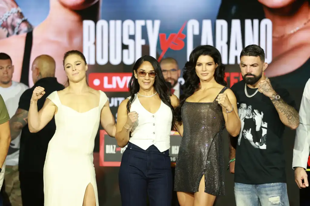 Group of four adults posing on a stage with a bold backdrop, fists raised in a display of camaraderie or competition.`