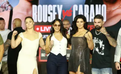 Group of four adults posing on a stage with a bold backdrop, fists raised in a display of camaraderie or competition.`