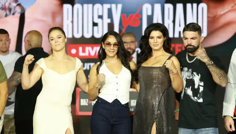Group of four adults posing on a stage with a bold backdrop, fists raised in a display of camaraderie or competition.`