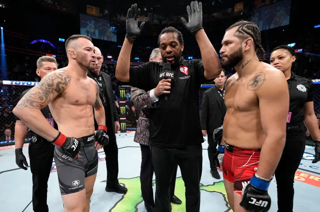 gettyimages-1380970173 - AfroCombat Two muscular UFC fighters face off in the octagon as the referee raises his arms to start the staredown.