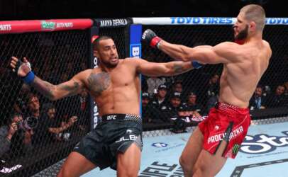 Two UFC fighters exchange punches inside the cage during a match: left fighter in black shorts with tattoos, right fighter in red shorts lunging with a punch.