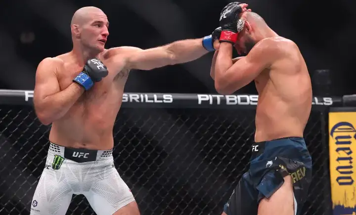 Two UFC fighters clash in the cage as one lands a punch to his opponent's head while the other guards with raised gloves.