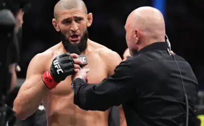 UFC fighter with a beard speaks into a microphone held by a presenter in a black shirt during a post-fight interview.