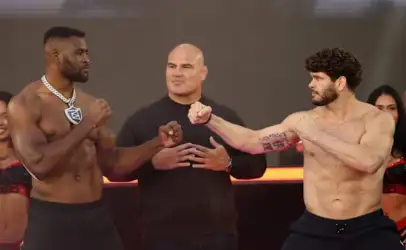 Two muscular fighters in a facing-off pose with fists raised, a referee standing between them on a stage.