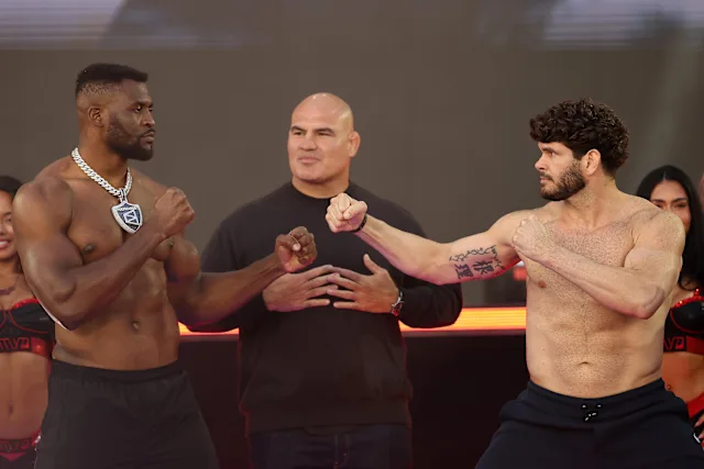 Two muscular fighters in a facing-off pose with fists raised, a referee standing between them on a stage.