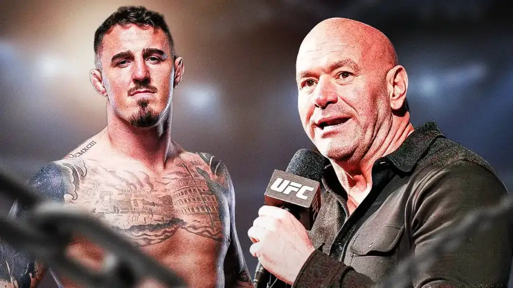 Tattooed male fighter shirtless beside a bald interviewer with a UFC mic on a well-lit stage.
