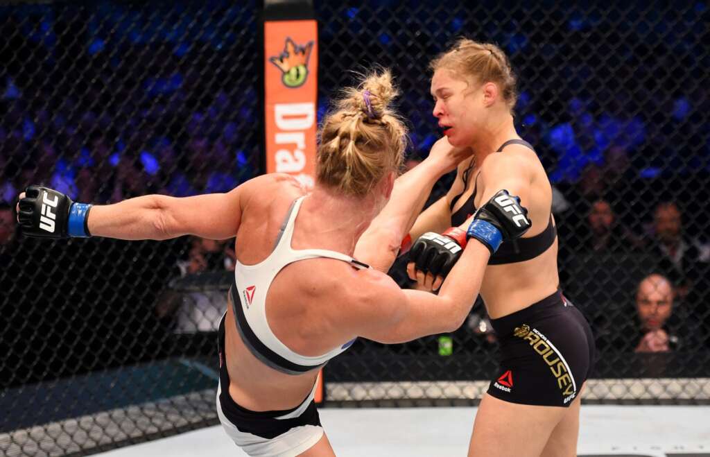 GettyImages-497205582-scaled - AfroCombat Two female UFC fighters in the octagon trading blows, one in a white top and the other in black shorts.