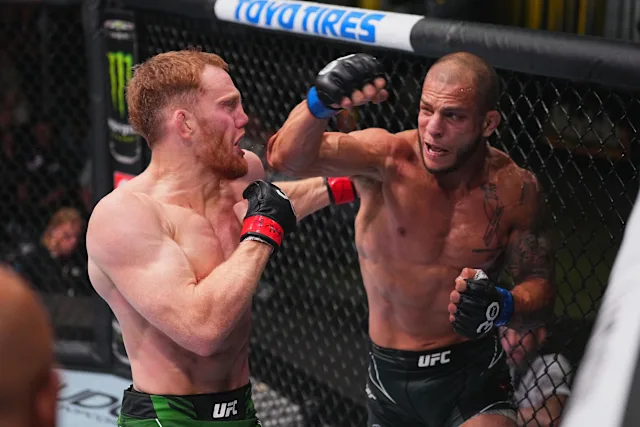 Two shirtless UFC fighters clash inside the octagon, one throwing a punch as the other guards with a raised fist.