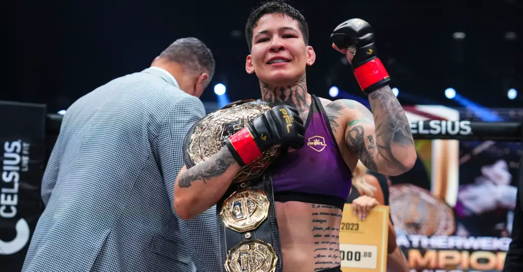 Female fighter in a purple outfit with multiple championship belts, fists raised in victory in a ring, a man in a suit congratulating her nearby.
