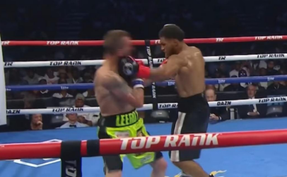 Two shirtless boxers trade punches inside a ring with red, white, and blue ropes marked 'TOP RANK' and 'DAZN' in the background.