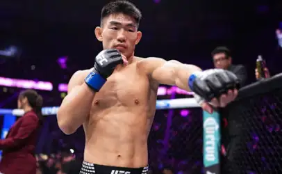 UFC fighter in the octagon delivering a punch with blue gloves, shirtless and focused.
