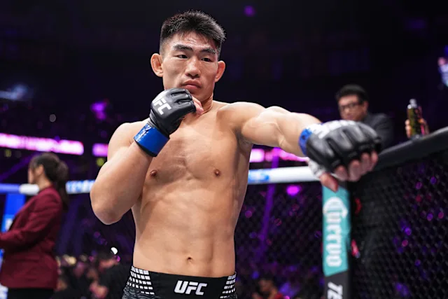 UFC fighter in the octagon delivering a punch with blue gloves, shirtless and focused.