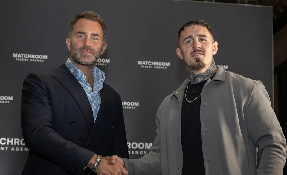 Two men shake hands in front of a black backdrop with Matchroom logos at a media event.