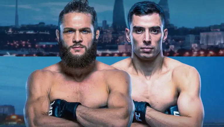 Two muscular men shirtless with UFC gloves cross their arms, posing in front of a city skyline backdrop.