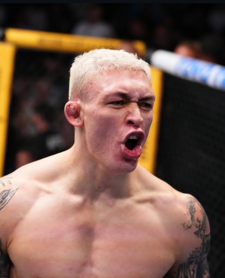 MMA fighter with bleached hair shouting inside a cage during a match.