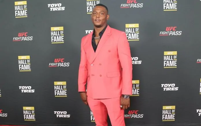 Jamahal-Hill-696x437 - AfroCombat Man wearing a bright pink suit posing on a red carpet with UFC Hall of Fame backdrop behind him