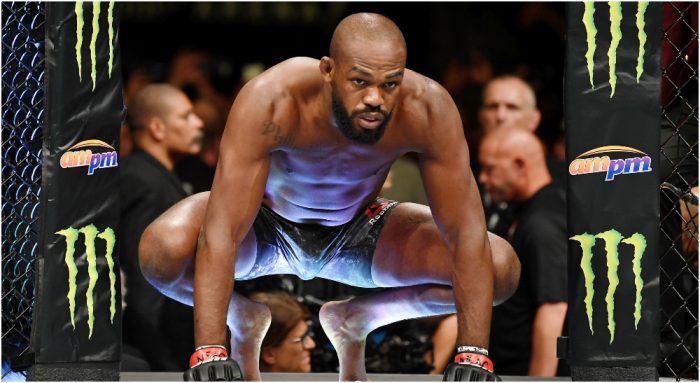 Male MMA fighter crouching in the octagon, wearing blue gradient shorts and red gloves, ready to start a bout.