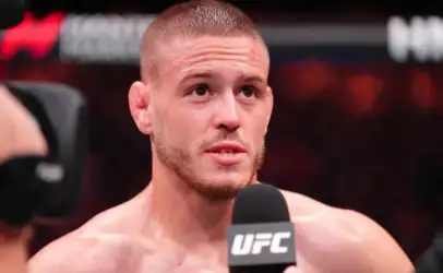 Male UFC fighter answering questions during a post-fight interview, holding a UFC-branded microphone in the octagon.
