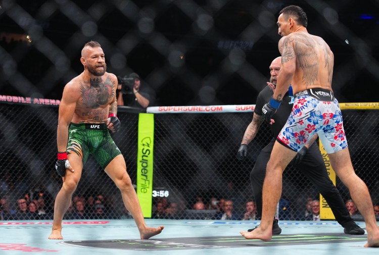 Two UFC fighters face off inside the octagon; left in green shorts with tattoos, right in floral shorts, referee between them.