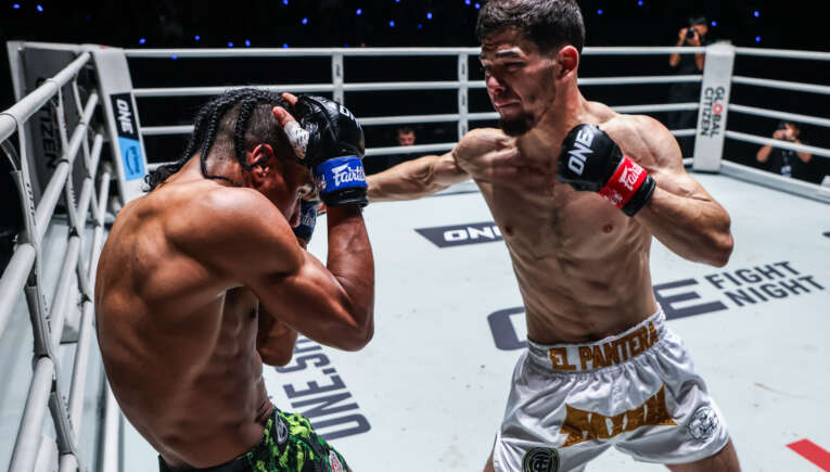 Two shirtless fighters exchange punches inside a boxing ring; one throws a right hand toward the other.