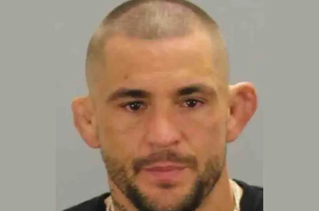 Mugshot of a man with short hair and stubble against a gray backdrop.
