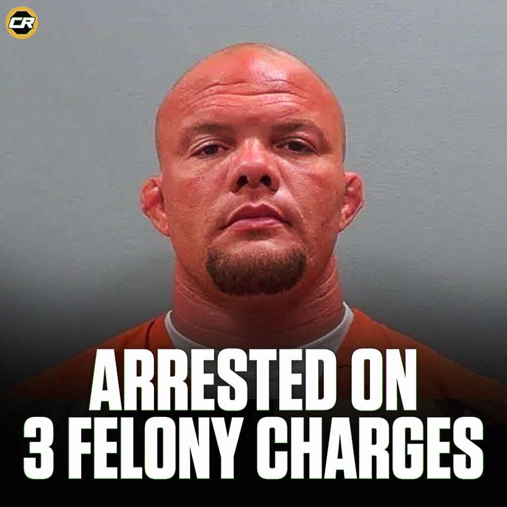 Mugshot of a bald man in an orange jumpsuit against a gray background, with a bold caption reading 'ARRESTED ON 3 FELONY CHARGES' at the bottom and a small circular logo in the top-left corner.