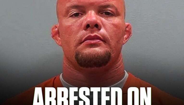 Mugshot of a bald man in an orange jumpsuit against a gray background, with a bold caption reading 'ARRESTED ON 3 FELONY CHARGES' at the bottom and a small circular logo in the top-left corner.