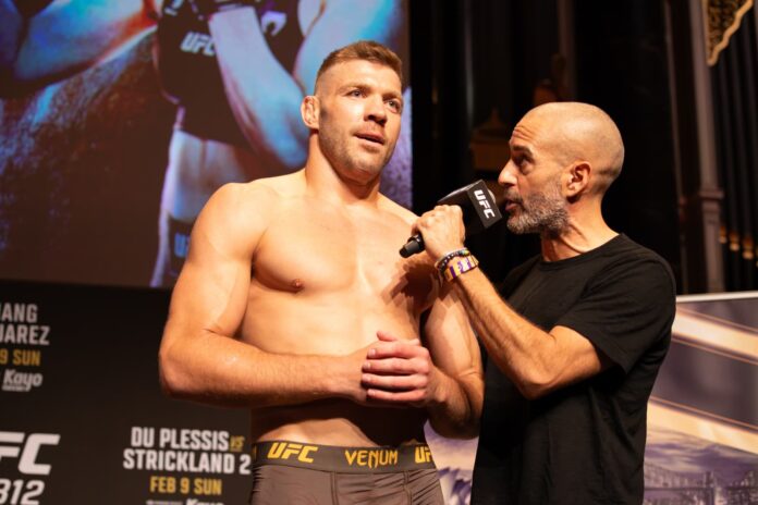 UFC fighter stands shirtless on stage while interviewer holds a microphone to him.