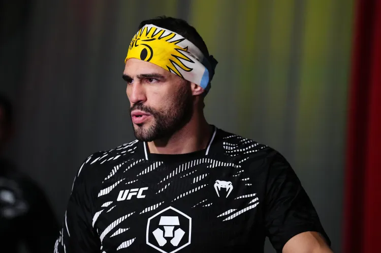 Male UFC fighter wearing a yellow sun-pattern headband and black training jersey with white logos on a dim background