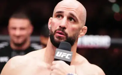 Bald, bearded male MMA fighter speaks into a UFC microphone during a post-fight interview.