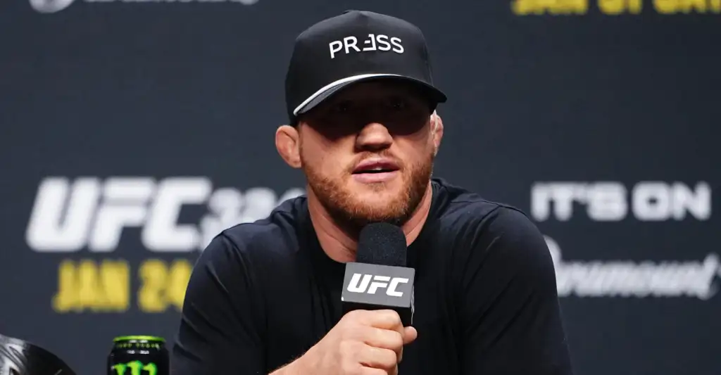 UFC fighter wearing a black cap that reads PRESS, speaking into a UFC microphone at a press conference.