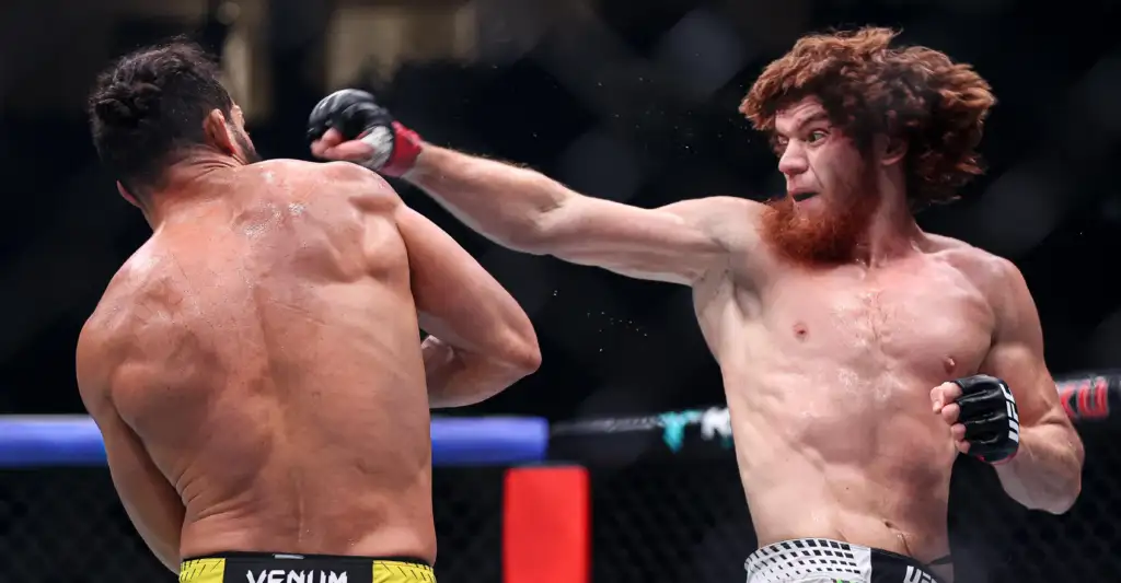 Two shirtless male mixed martial artists clash in a cage as one lands a punch on the other.