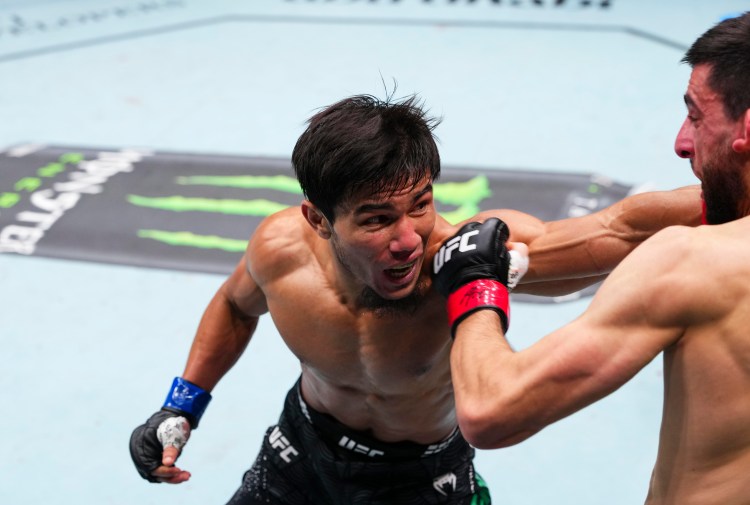 gettyimages-2286951690 - AfroCombat Two shirtless UFC fighters exchange a punch in the octagon, with one fighter landing a punch to the other's face while both wear UFC gloves.