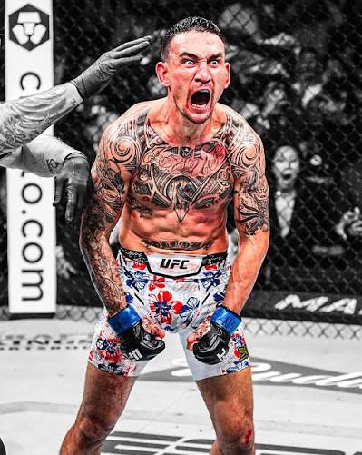 Tattooed UFC fighter roars with fists clenched in the cage, wearing floral shorts and blue gloves.