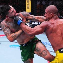 Two UFC fighters collide in the octagon; one in green shorts with blue gloves punches a bald opponent in yellow shorts.