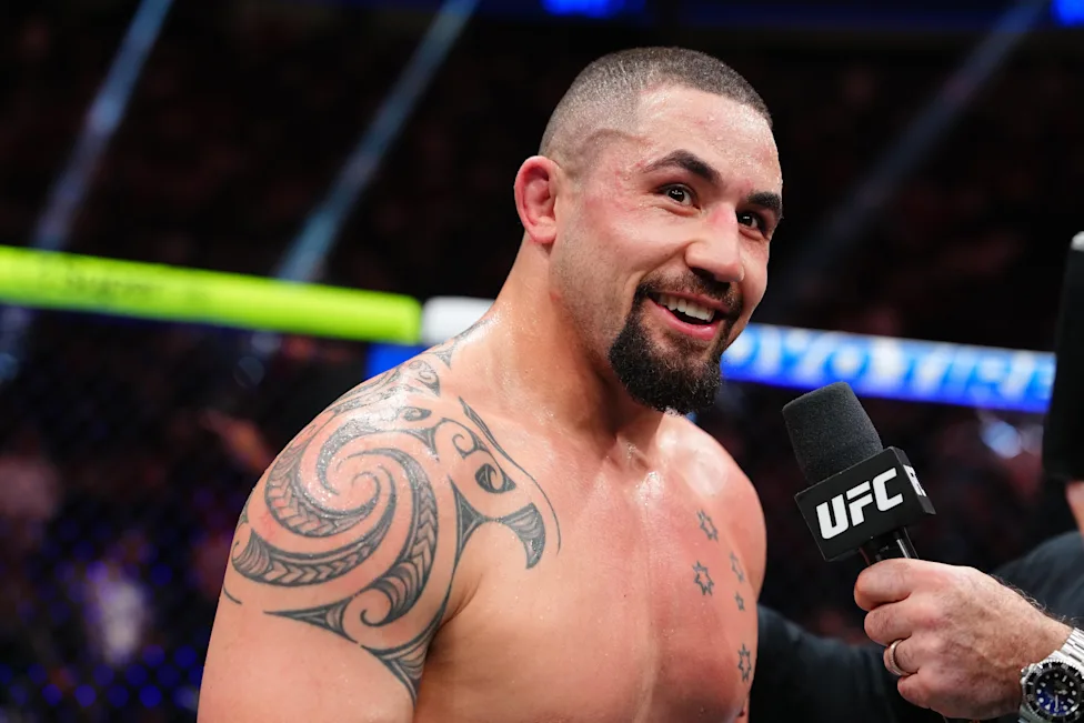 Muscular, tattooed MMA fighter smiles during a post-fight interview with a UFC mic.