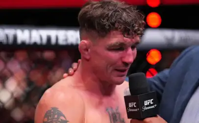 MMA fighter being interviewed in the UFC arena, microphone labeled UFC held close to his mouth as he speaks.