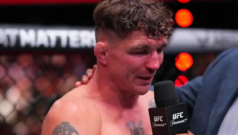 MMA fighter being interviewed in the UFC arena, microphone labeled UFC held close to his mouth as he speaks.
