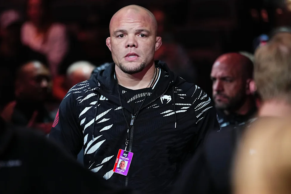 79e2b877a6005738c9645c788df9fda5 - AfroCombat Bald man wearing a black patterned hoodie with a lanyard and event ID badge, in a crowded arena.
