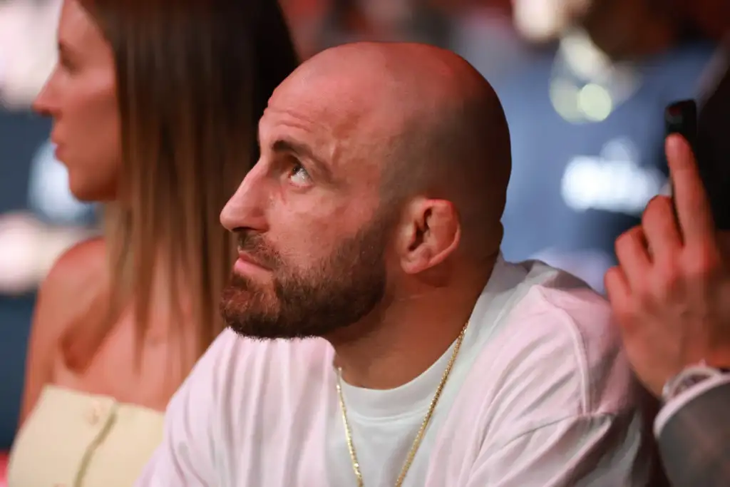 GettyImages-2198484983-scaled - AfroCombat Close-up of a bald man with a beard looking to the left at a social event; wearing a white shirt and gold chain.
