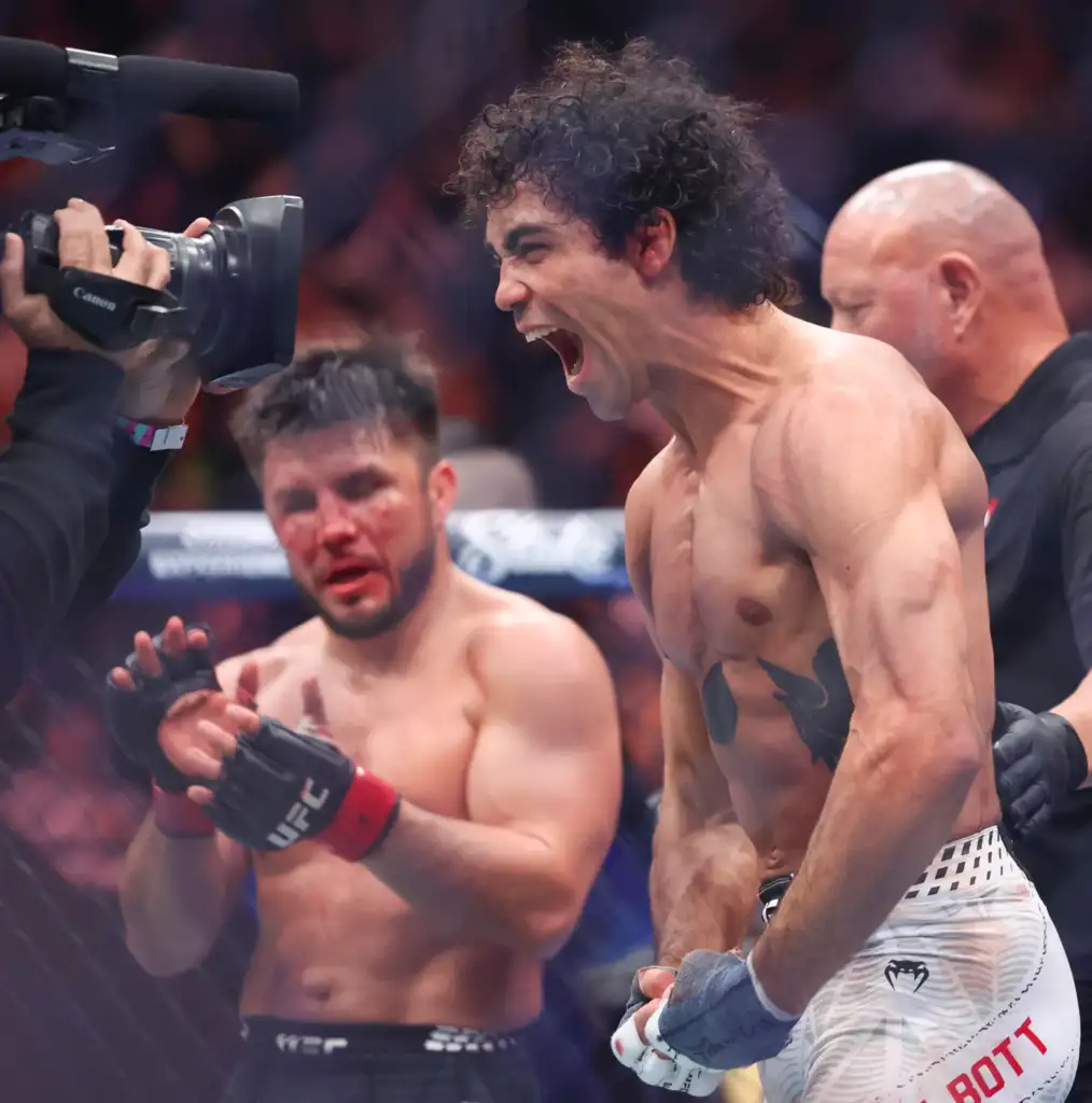 gettyimages-2251289668 - AfroCombat Shirtless boxer shouting in celebration in a boxing ring, as a cameraman films from the left.