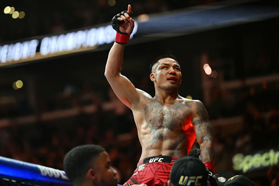 58f085b2303e03c6313ca88dbce669be - AfroCombat UFC fighter with tattoos raises his right fist in celebration inside the octagon after a victory.