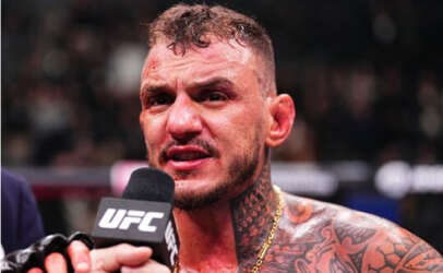 UFC fighter speaks into a microphone after a fight, shirtless with tattoos and a focused expression