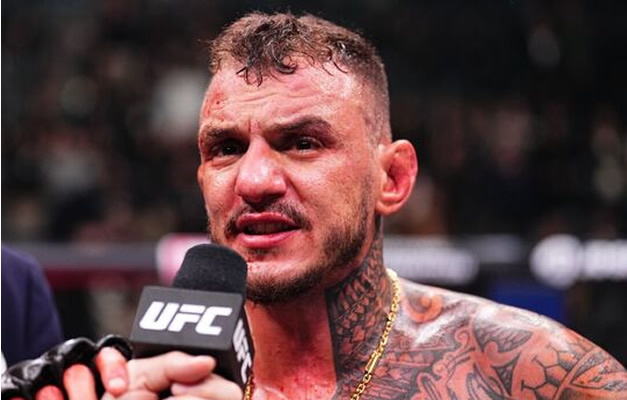 UFC fighter speaks into a microphone after a fight, shirtless with tattoos and a focused expression