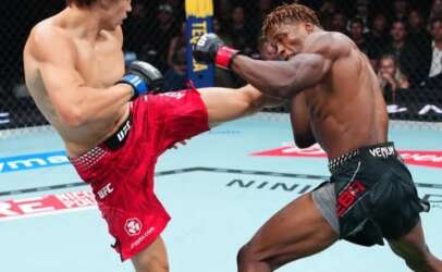 Two UFC fighters clash inside the cage as one lands a high kick on the other’s body during a bout.