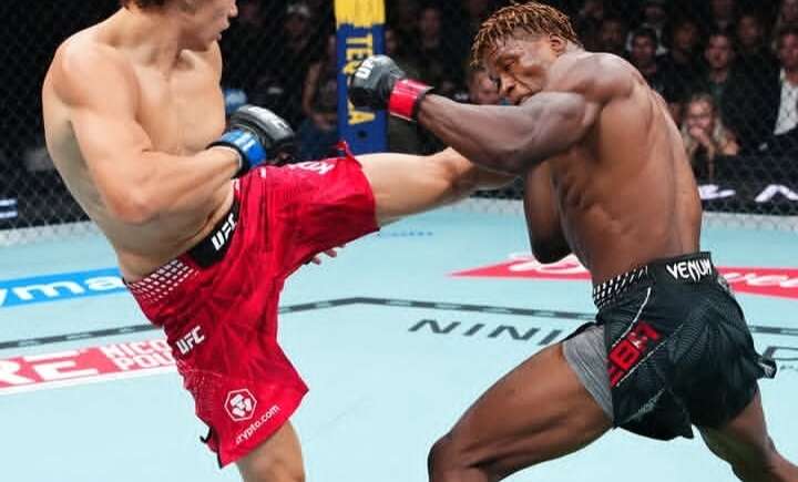 Two UFC fighters clash inside the cage as one lands a high kick on the other’s body during a bout.