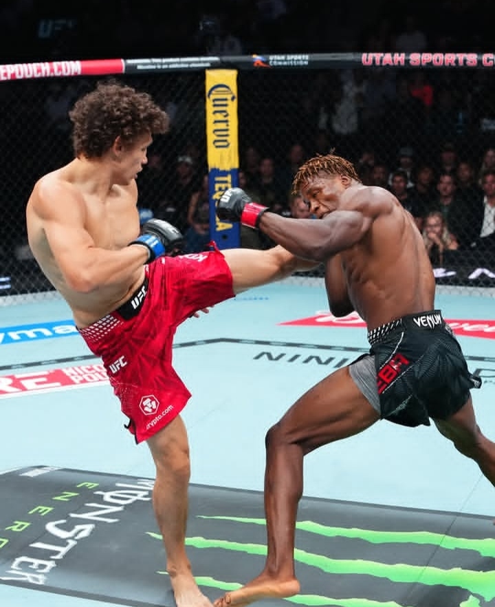 Two UFC fighters clash inside the cage as one lands a high kick on the other’s body during a bout.