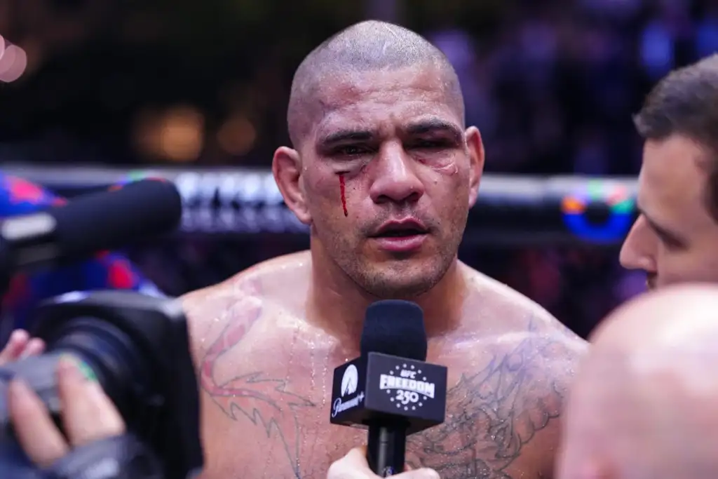 Male mixed martial artist with a bloodied face being interviewed after a fight, microphone in front of him