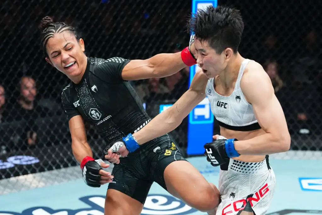 Two female UFC fighters exchange a punch in the octagon, one in black gear landing a strike on the opponent in white.