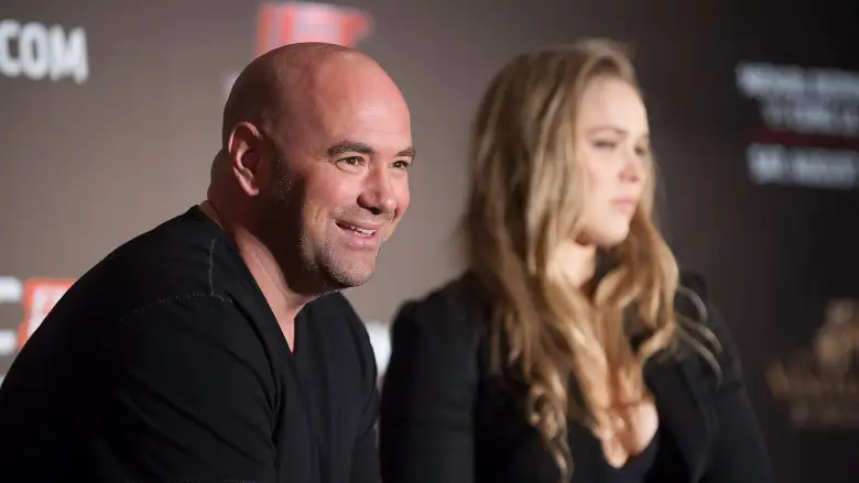 Two adults seated at a panel discussion, with the man smiling toward the audience and the woman looking ahead beside him.